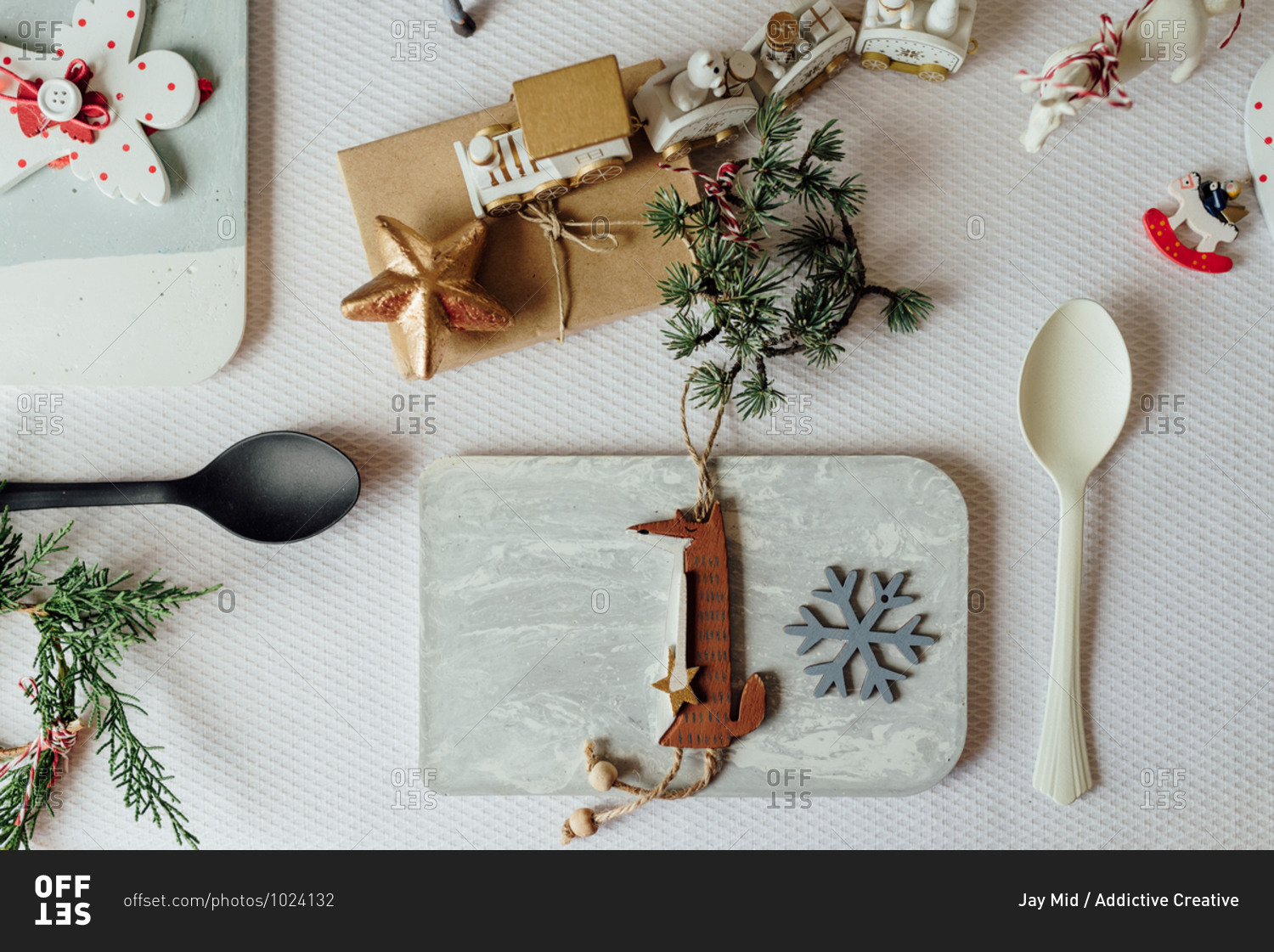 Top view composition with decorative snowflake and wooden fox figure hanging on pine tree branch arranged near spoon on table during Christmas celebration