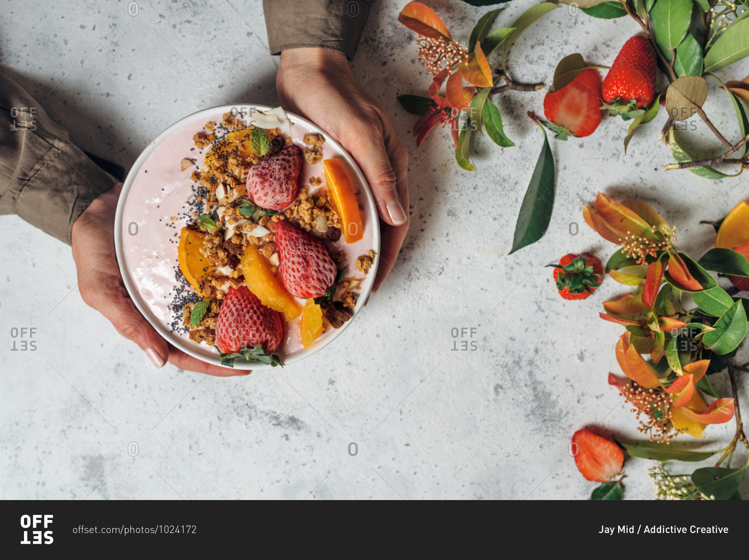 From above of unrecognizable female with smoothie bowl with fruits and berries sitting at table during breakfast in morning