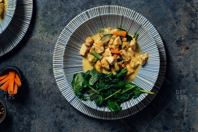 Delicious Thai Curry Coconut Chicken, accompanied by tender vegetables and spinach, in a modern blue plate