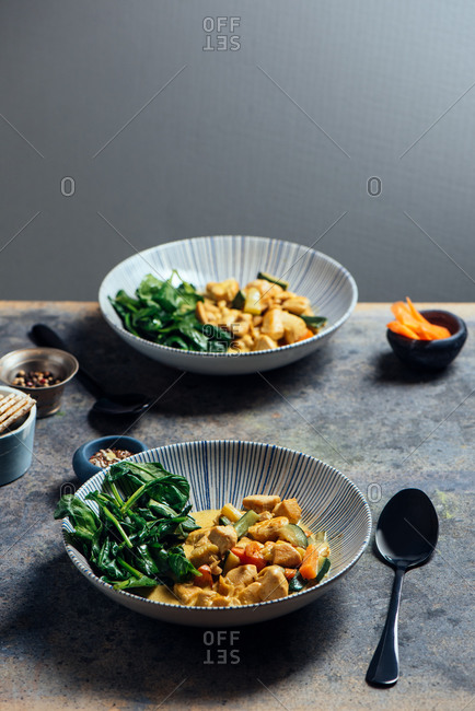 Delicious Thai Curry Coconut Chicken, accompanied by tender vegetables and spinach, in a modern blue plate