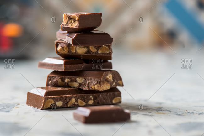 Closeup of stacked broken pieces of chocolate bar with nuts placed on table
