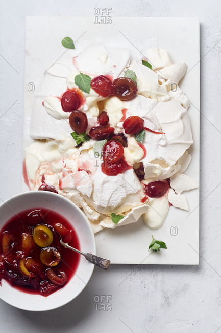 Pavlova meringue cake with fresh mint and wine poached plums
