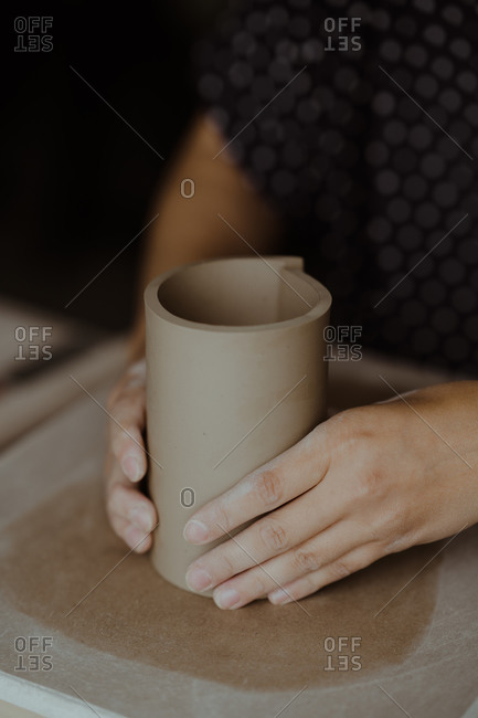 Close up of a woman's hands shaping clay into a cylinder
