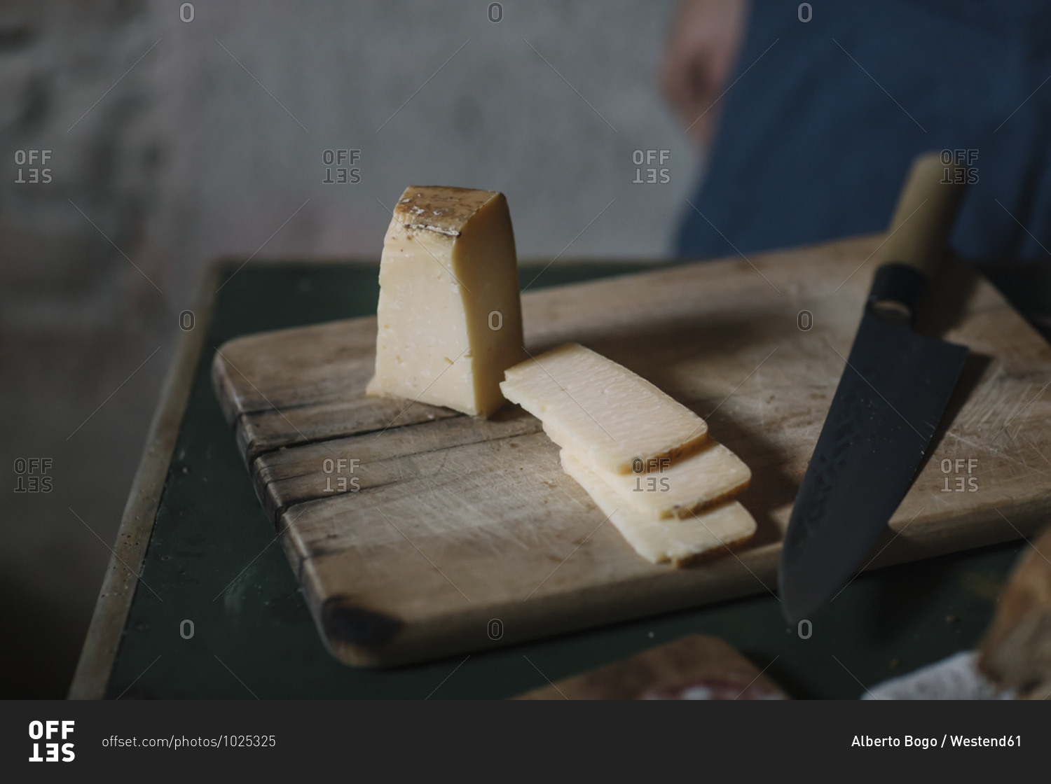 Close-up of artisanal cheese slices with knife on cutting board