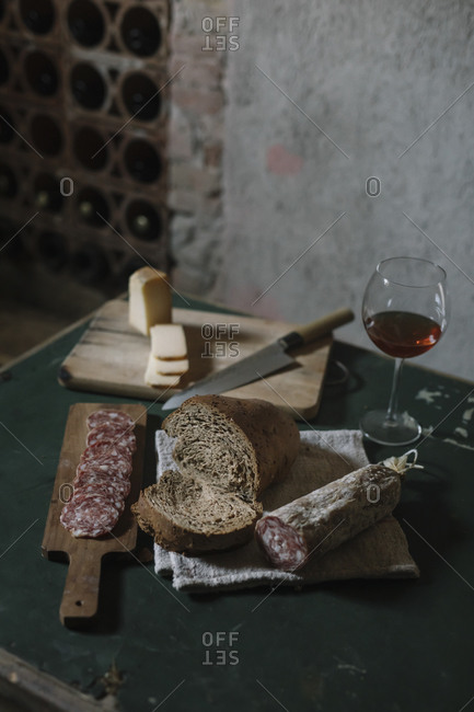 Fresh salami sausage with homemade bread and wine on table in cellar
