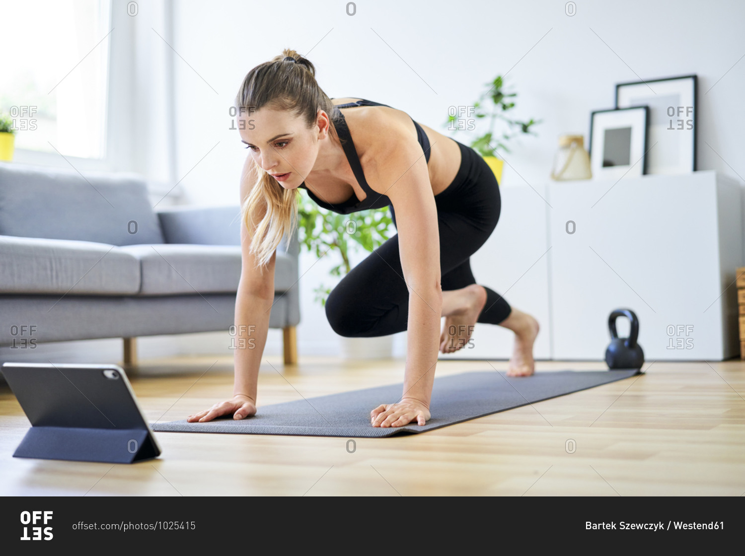Determined woman learning mountain climber exercise through internet on digital tablet