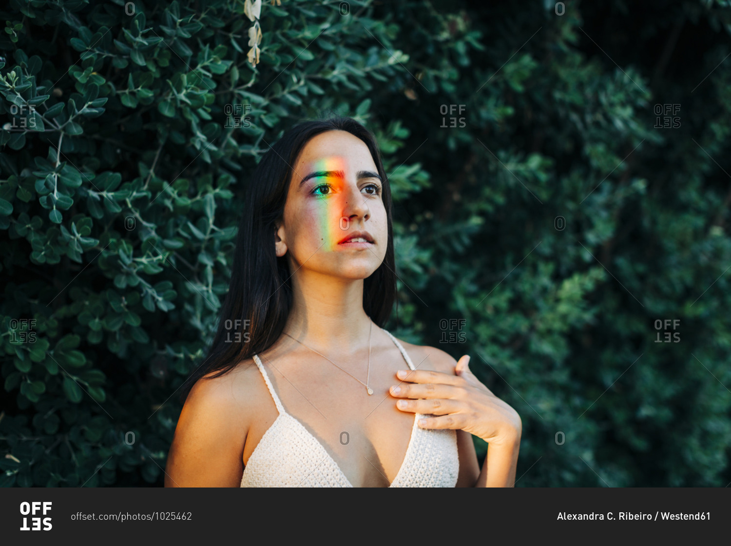 Young woman with multi colored light on face standing at park