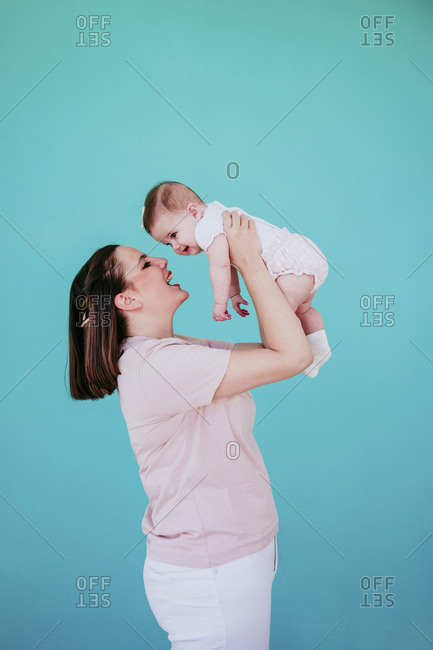 Mother and baby girl in front of turquoise wall