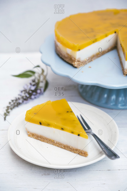 Slice of layered tart with crumble crust- coconut milk- custard and passion fruit top