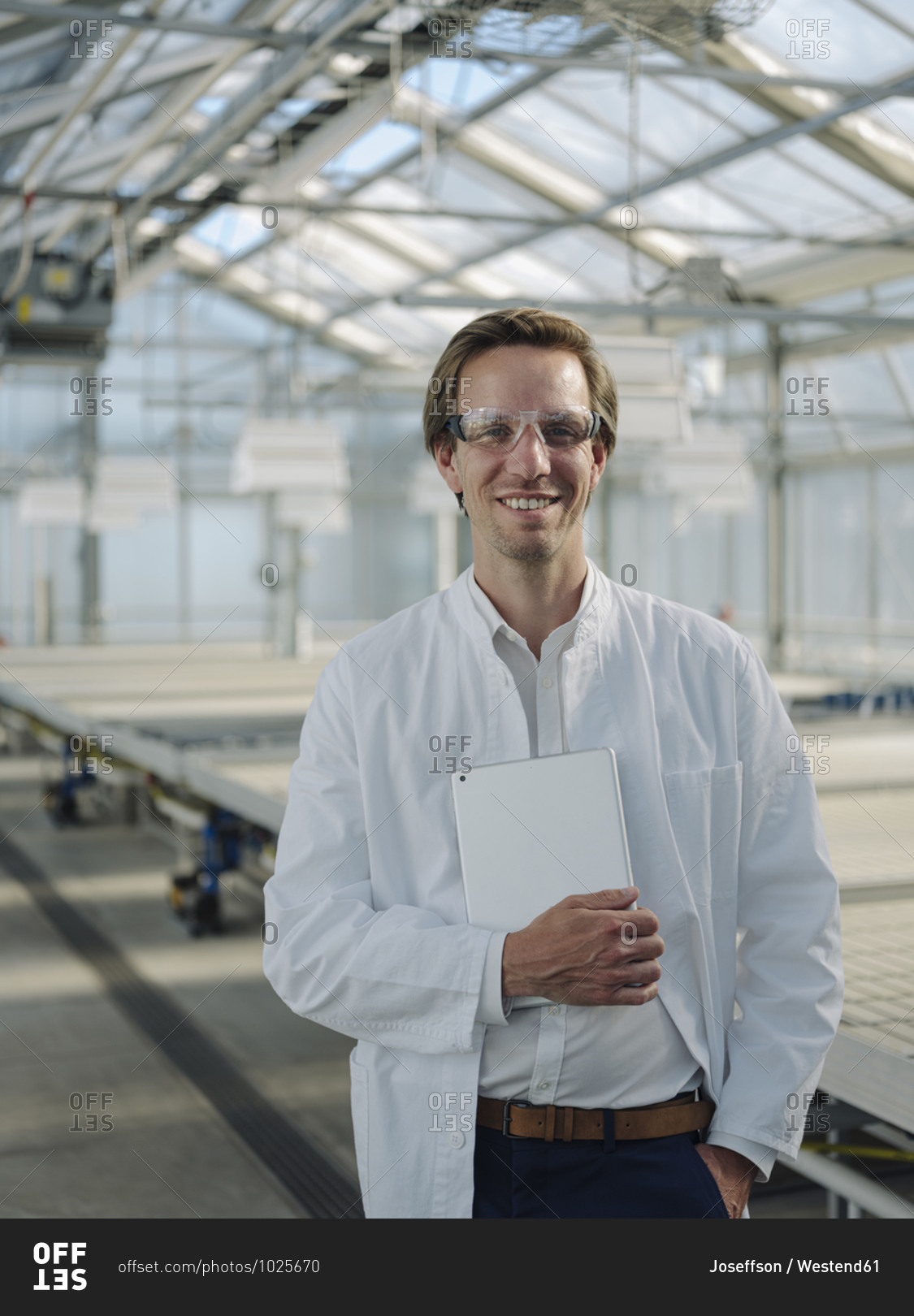 Portrait of a smiling scientist holding tablet in a greenhouse