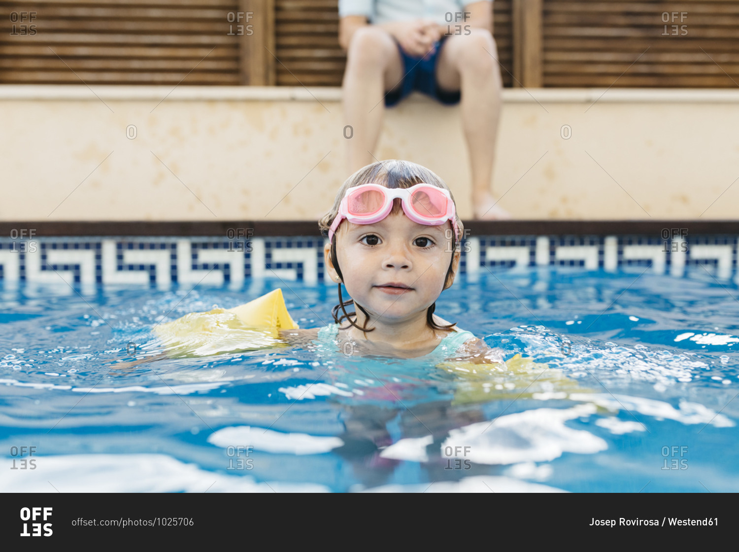 Little girl with swimming goggles in swimming pool