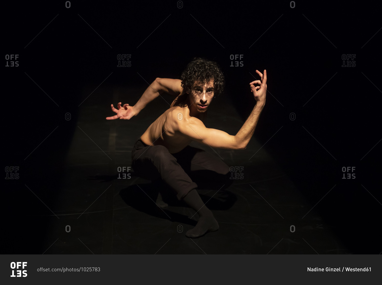 Male ballet dancer performing on black stage