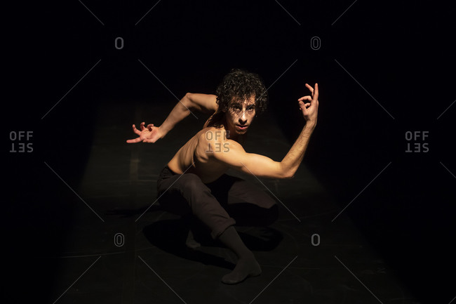 Male ballet dancer performing on black stage