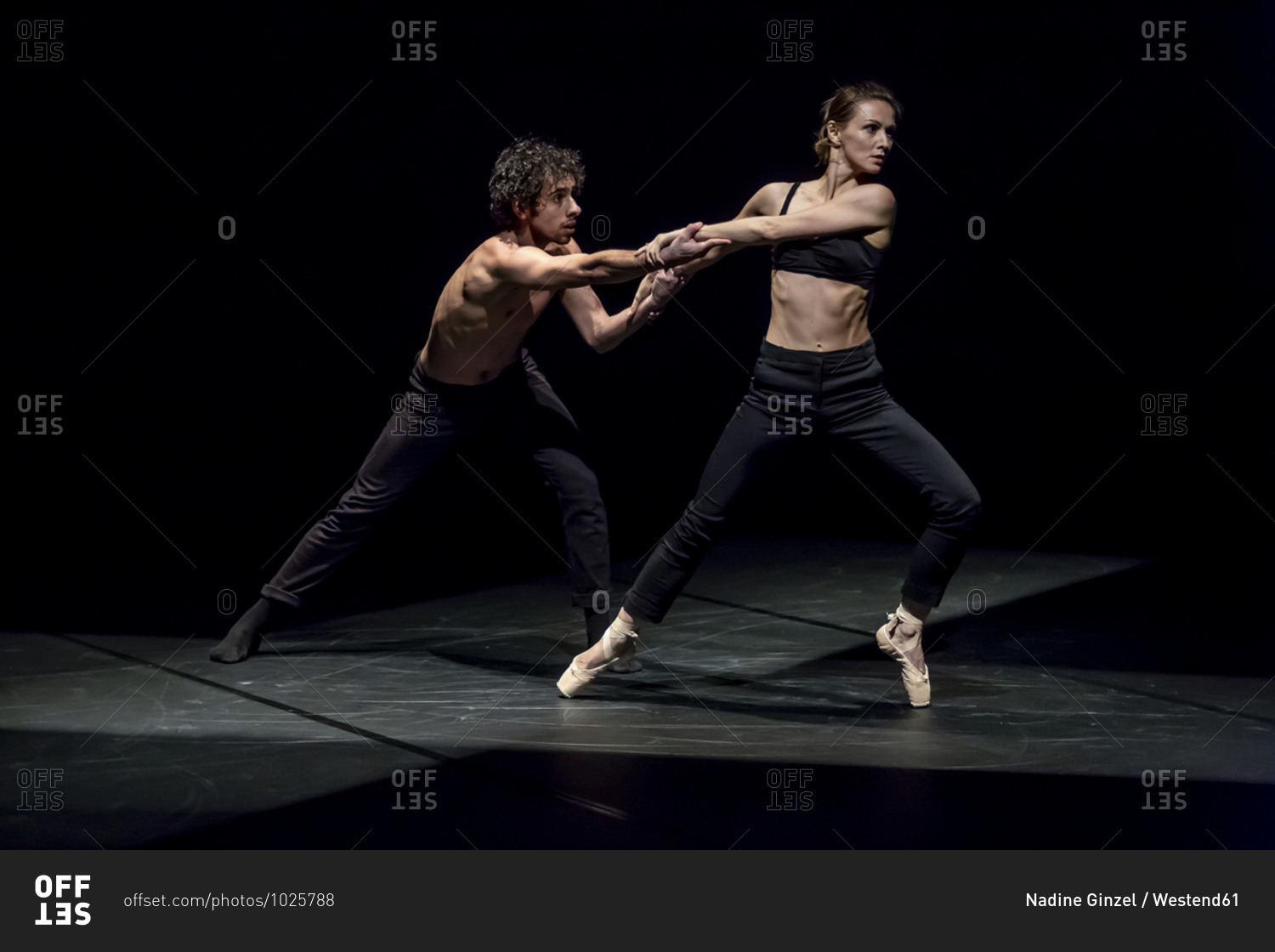 Male and female dancer performing contemporary ballet on black stage