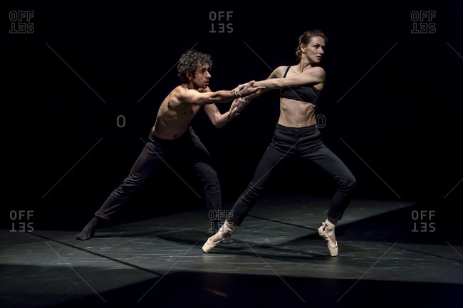 Male and female dancer performing contemporary ballet on black stage