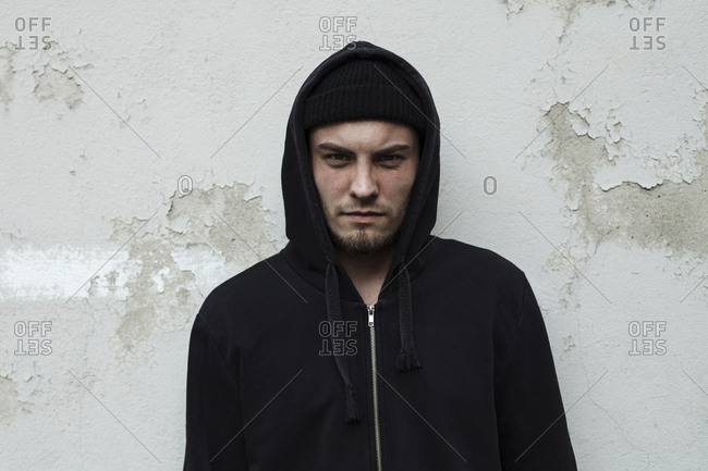Man wearing hoodie standing against wall