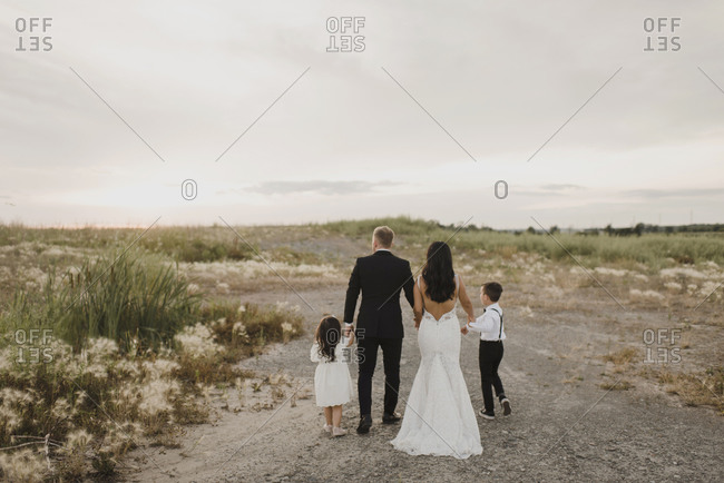 Parents and children wearing wedding dress while walking in field against sky