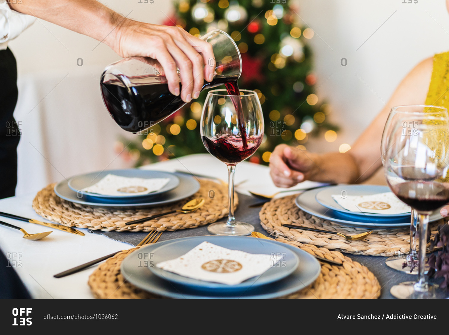 Crop view of hand of anonymous old man serving red wine during Christmas dinner