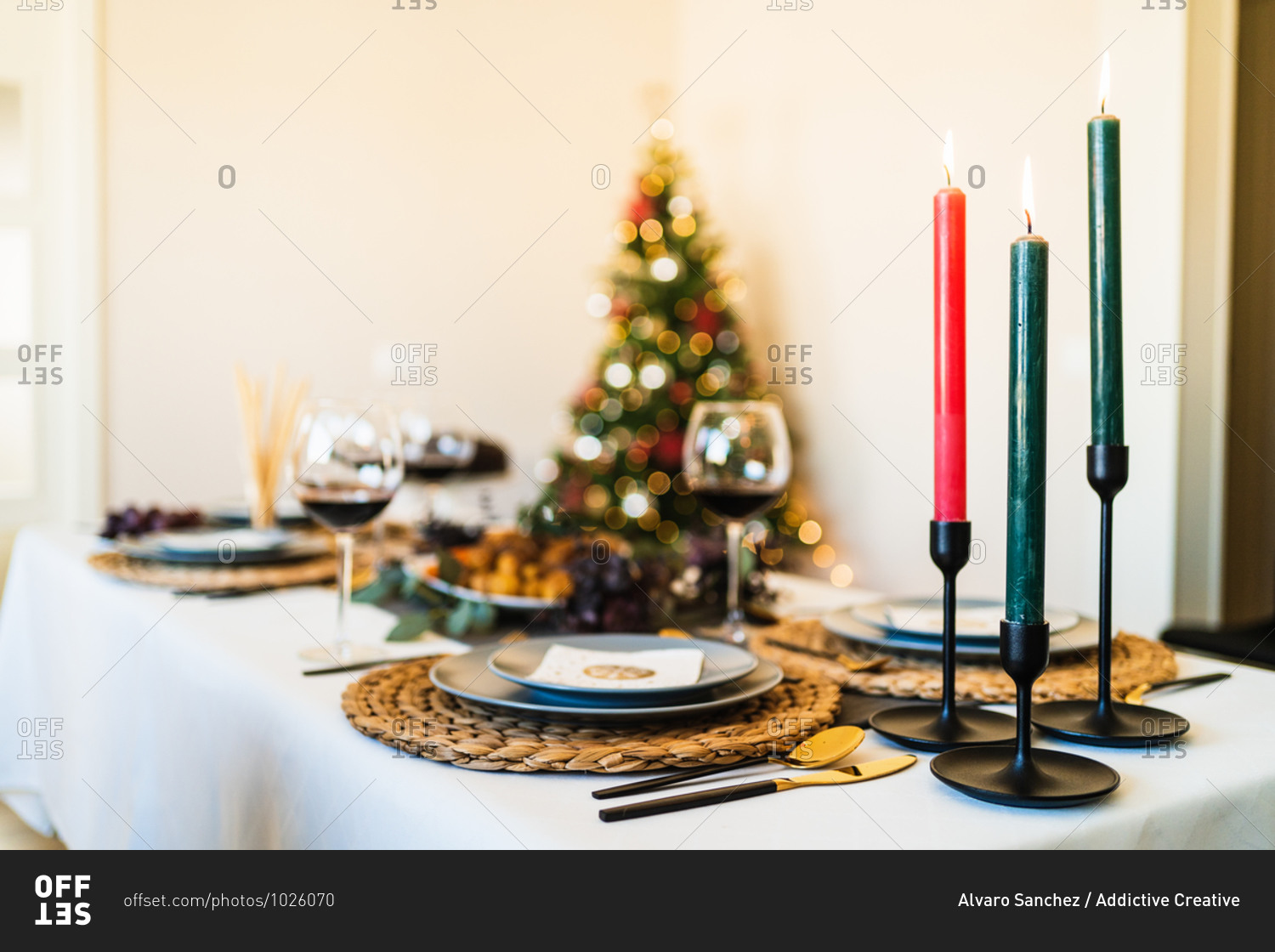 Festive table setting near decorated Christmas tree with glowing garlands before Christmas celebration party