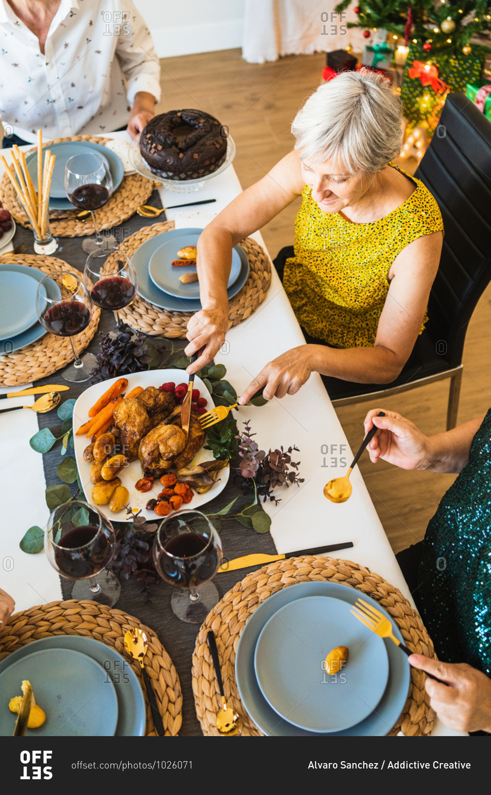From above of crop unrecognizable people enjoying tasty dish while sitting at table during Christmas holiday