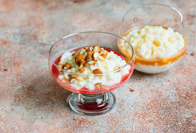 Rice pudding desserts with berry sauce, nuts and caramel sauce in glass dish