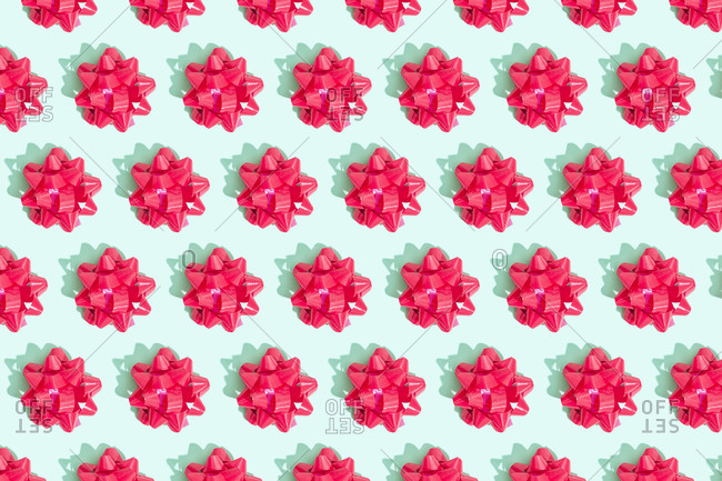 Pink gift bows arranged in a pattern on mint green background