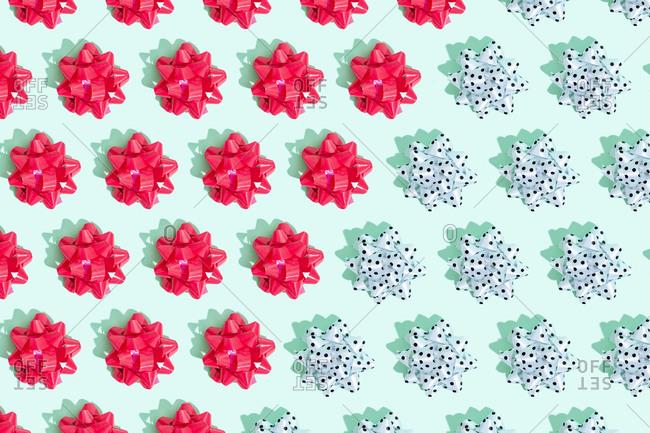 Pink and polka dot gift bows arranged in a pattern on mint green background