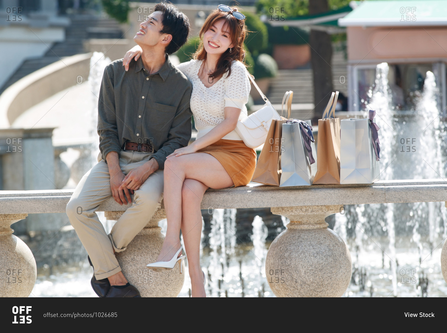 Happy couple sitting in front of fountain