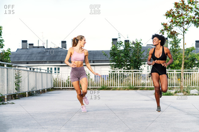 Sportive multiethnic females in activewear competing with each other while running fast together during training