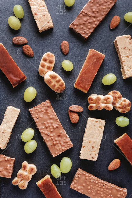 Top view of full frame background of sweet chocolate bars and cookies placed on table with grapes
