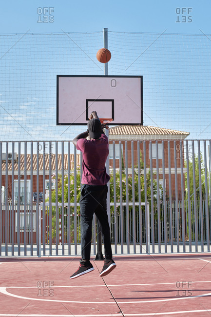 Young black man throwing the ball to the basketball basket