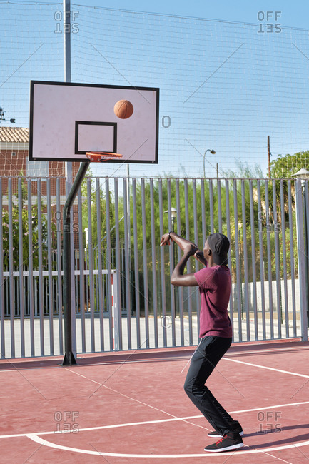 Young black man throwing the ball to the basketball basket