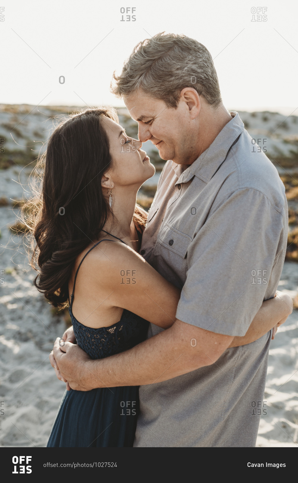 Mid-40's man and woman with closed eyes embracing and touching noses
