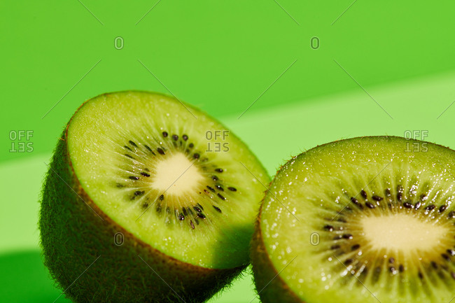 Half of delicious ripe kiwi fruit placed on green background in ...