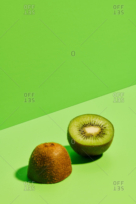 Half of delicious ripe kiwi fruit placed on green background in modern studio