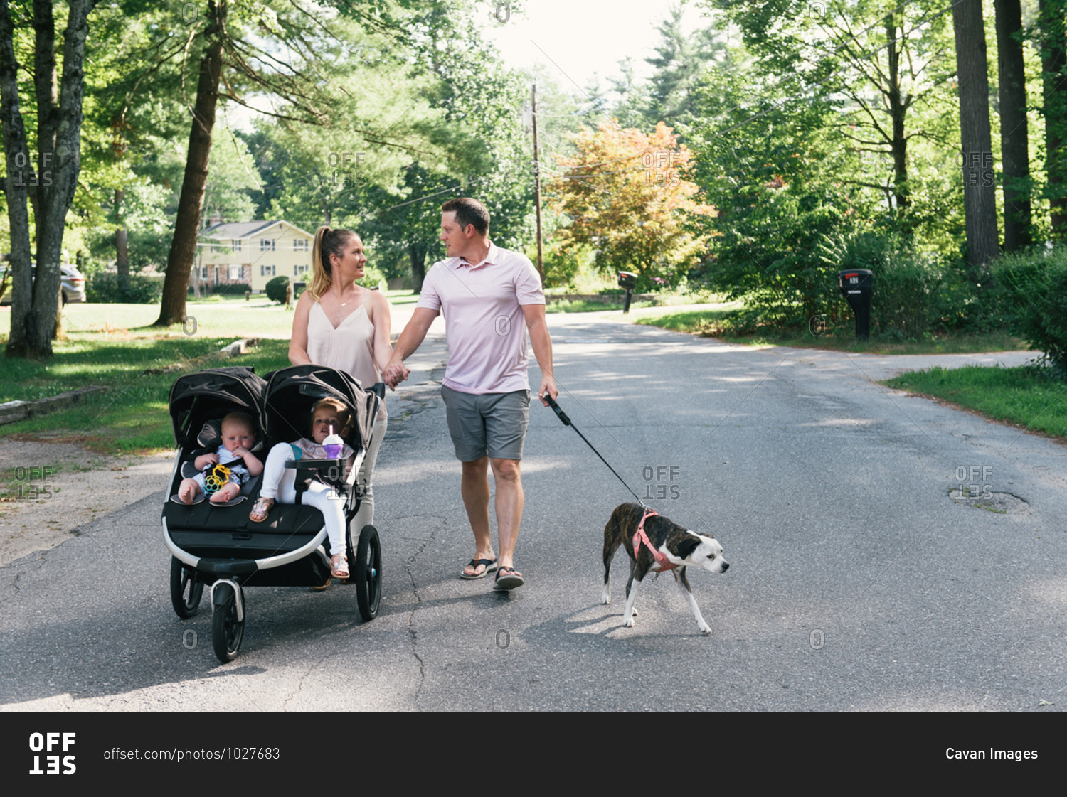 Young family walking down suburban street in stroller together