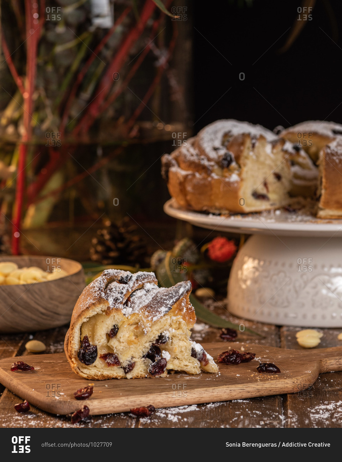 Sweet traditional Kringle with berries and powdered sugar placed on wooden table in kitchen