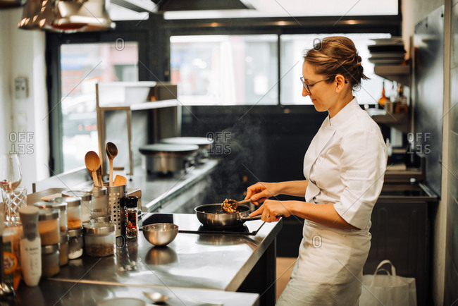 Female chef stirring hot food while working in restaurant kitchen