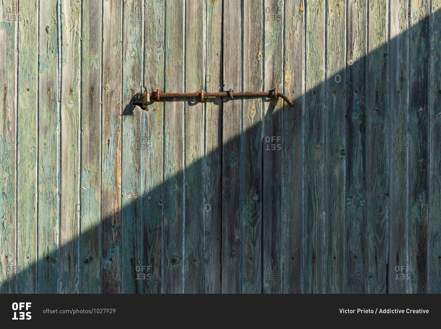 Weathered wooden door with rusty metal bolt on sunny day in Sa Caleta
