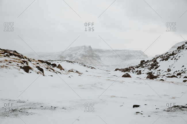 Picturesque view of mountainous terrain covered with white snow against gray sky on cold winter day in Faroe Iceland in Iceland