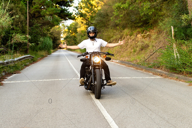 Young man on a vintage motorcycle on a mountain road at sunset