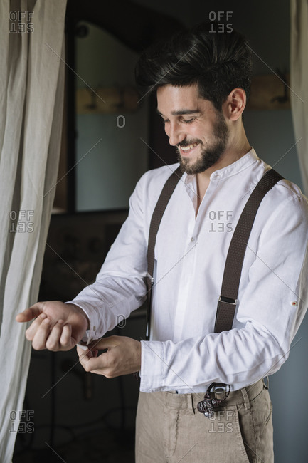 Smiling groom getting ready while standing at dressing room