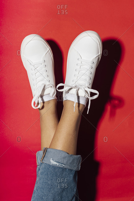 Close-up of woman legs crossed and feet up on red background