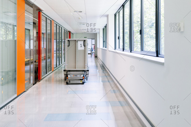 Robotic trolley with metallic container moving in hospital corridor