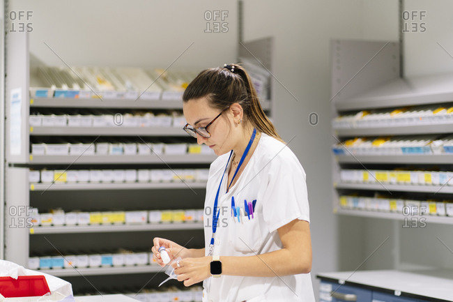 Female worker packing medicines while standing in pharmacy