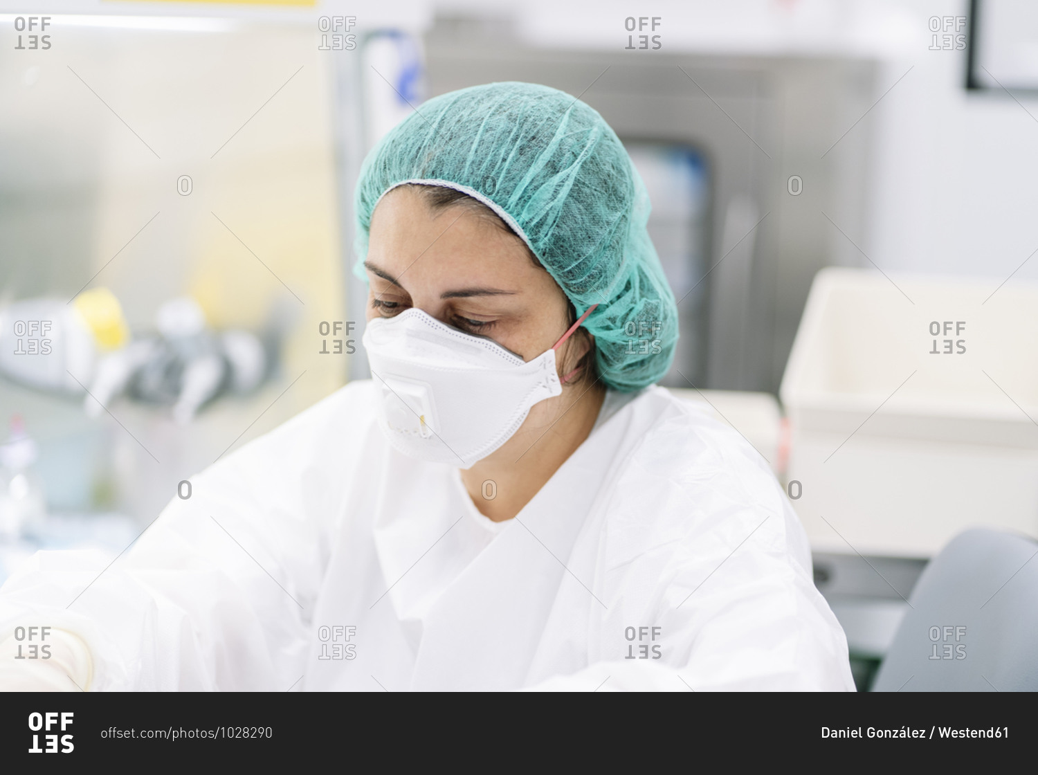 Close-up of female pharmacist wearing surgical mask and cap while working in laboratory