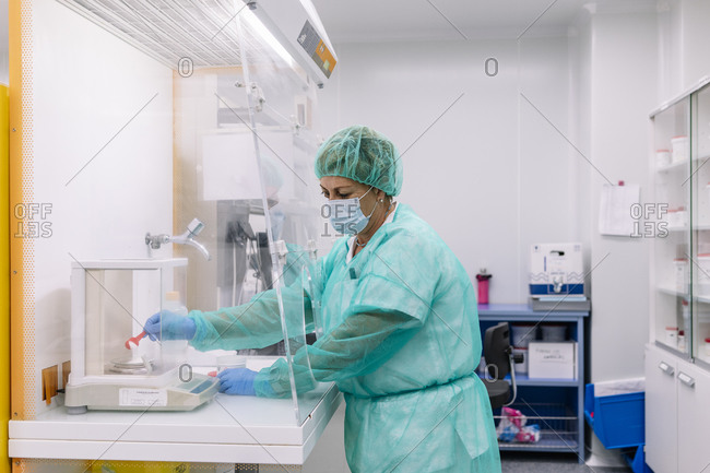 Female scientist measuring powder medicine on scale in laboratory