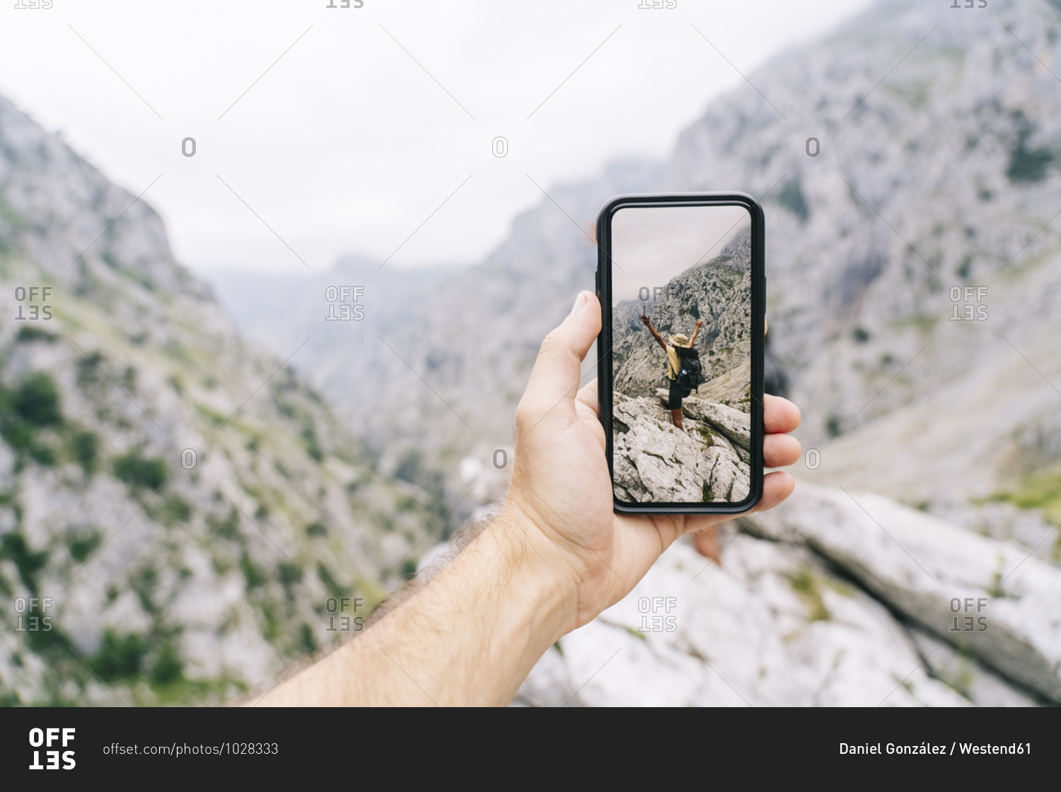 Man\'s hand holding phone while taking photo of carefree woman at Ruta Del Cares- Asturias- Spain