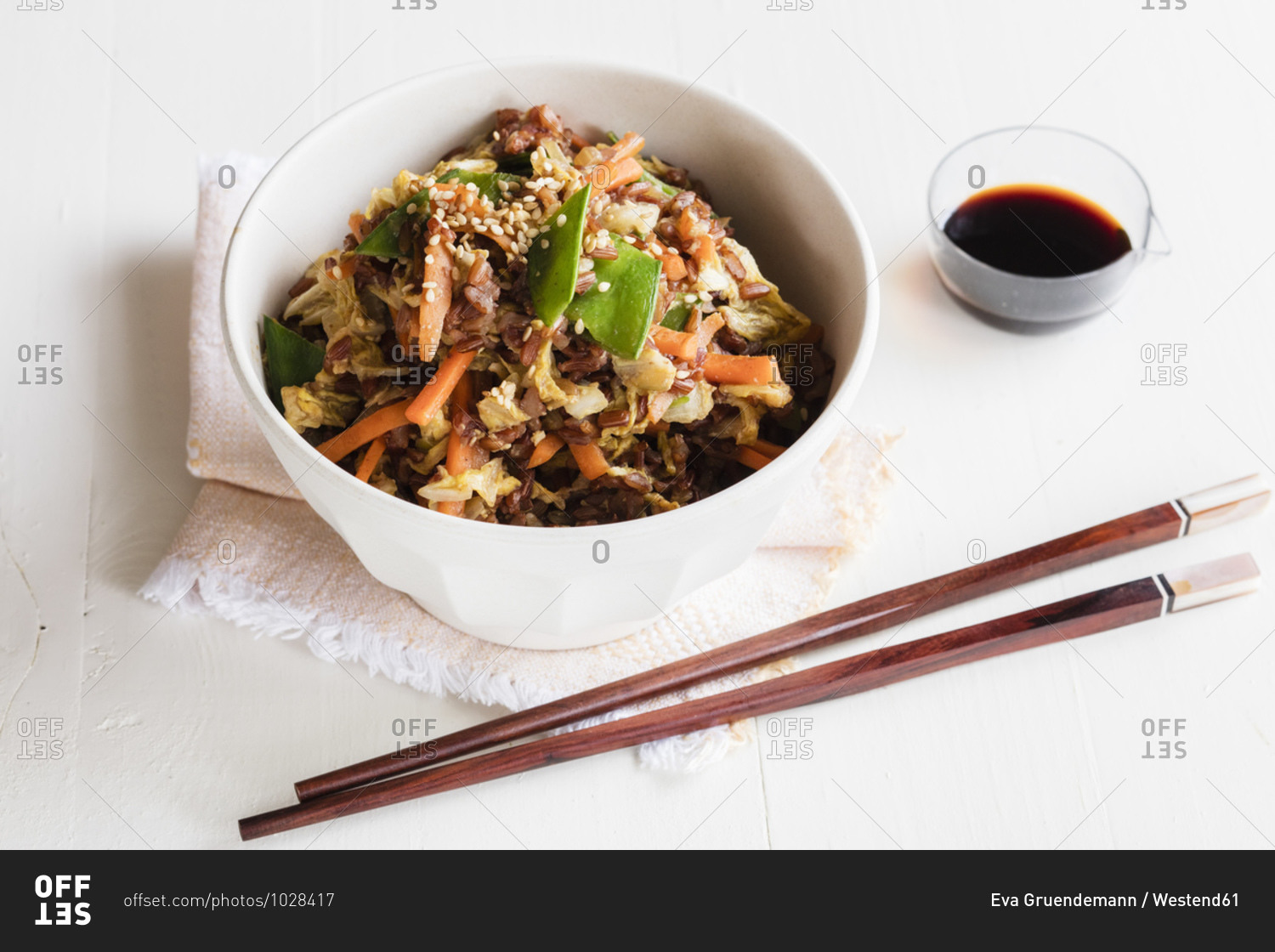 Chopsticks and bowl of fried red rice with vegetables