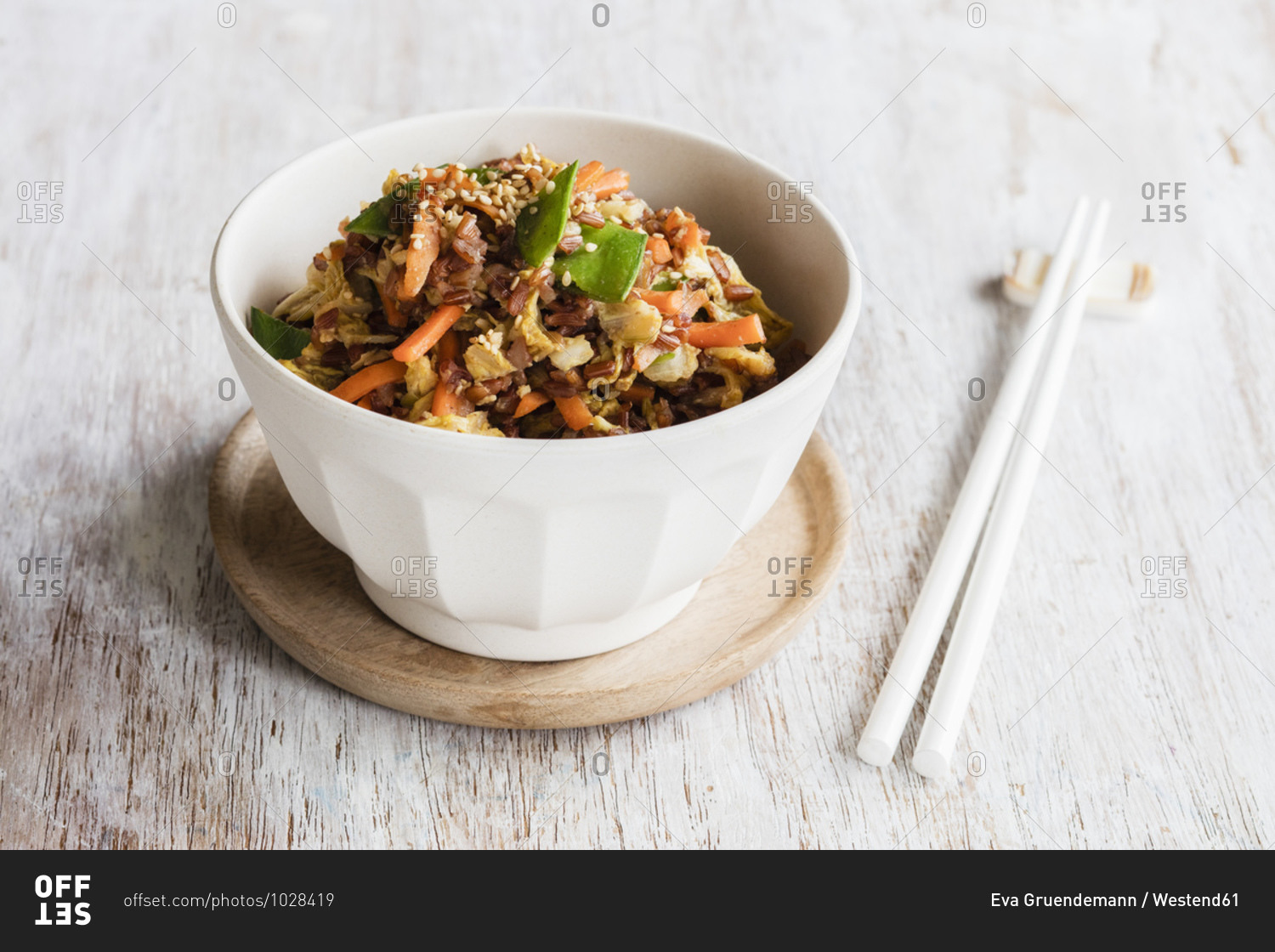 Chopsticks and bowl of fried red rice with vegetables